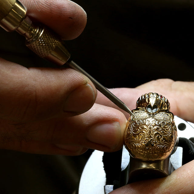 A tattoo engraved skull ring in yellow gold is getting pavé diamonds set in its eyes.